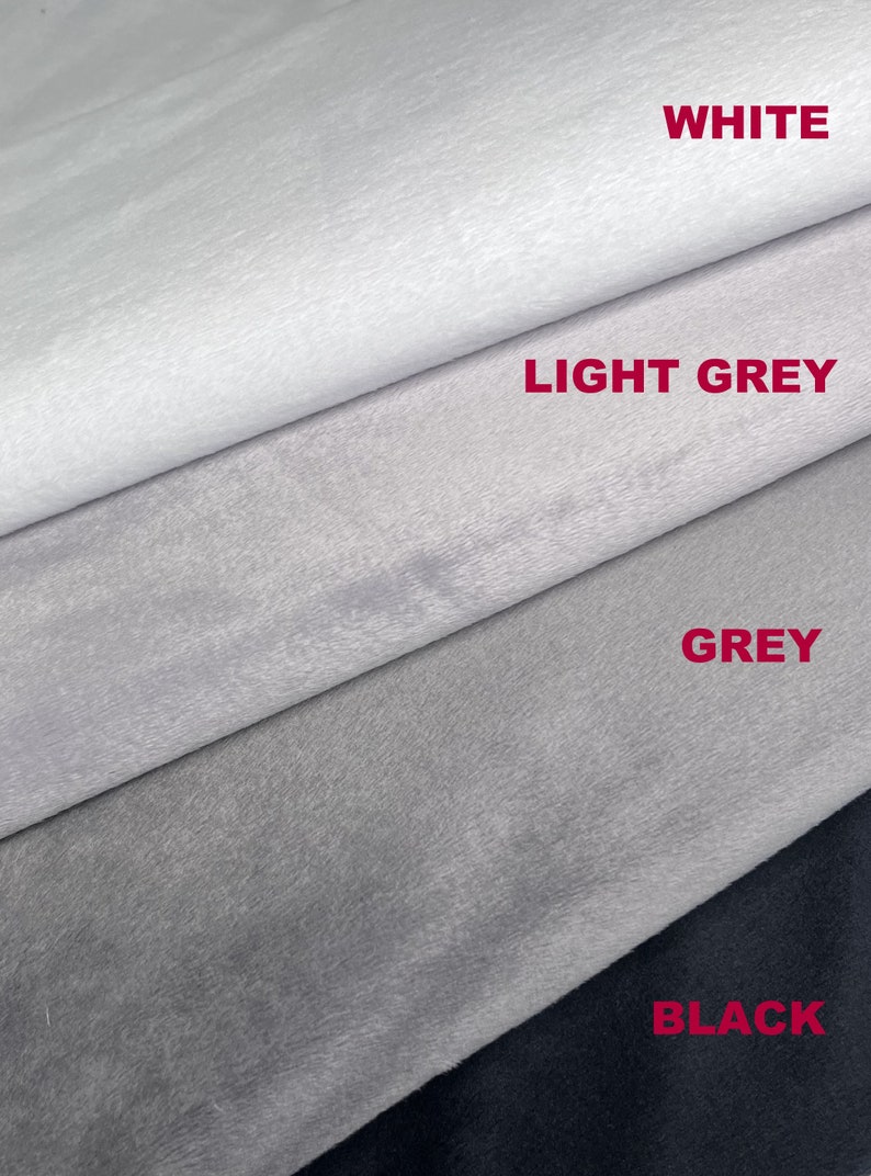 Op de afbeelding: Vier stofstalen in verschillende grijstinten, van wit tot zwart. De stalen zijn gelabeld met "WHITE", "LIGHT GREY", "GREY" en "BLACK".