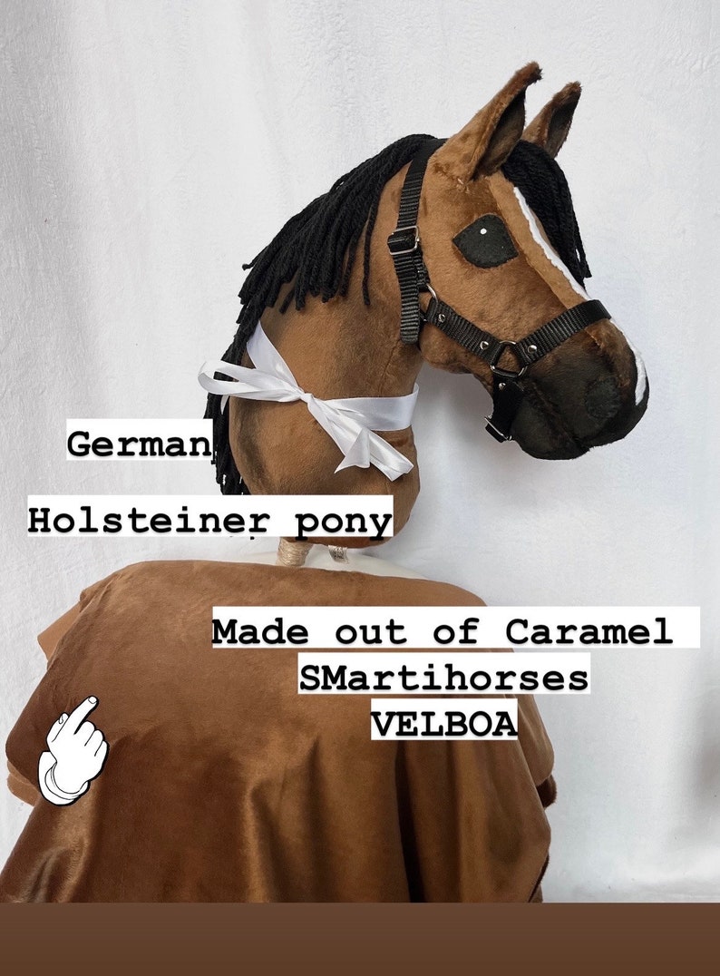 Op de afbeelding: Een bruin en wit Duits Holstein pony paardenhoofd gemaakt van caramel SmartIhorses Velboa stof. Het paard draagt een zwart halster en een wit lint.
