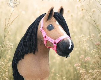 May include: A brown hobby horse toy with a black yarn mane, a white blaze on its face, and a bright pink halter. The horse features a circular logo in the top left corner and the text Handmade in Czech Republic at the top right.