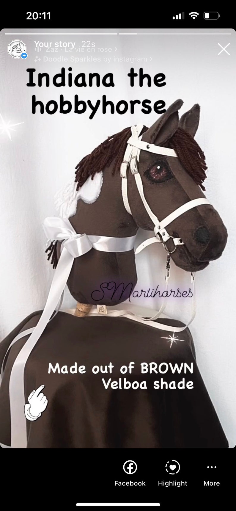 Op de afbeelding: Een bruin en wit hobbypaard met een wit hoofdstel en een wit lint. Het paard is gemaakt van bruin velboa-stof en heeft een witte ster aan de zijkant. De tekst "Made out of BROWN Velboa shade" staat onder het paard.