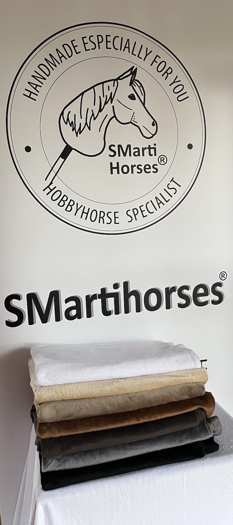 Puede incluir: Una pila de telas de felpa en varios colores, incluyendo blanco, beige, marr&oacute;n, gris y negro. La imagen presenta el texto "SMarti Horses" y "Hobbyhorse Specialist."