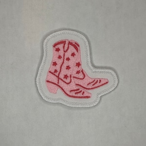 Può includere: Toppa ricamata a forma di stivale da cowboy rosa con cuciture bianche e un contorno bianco. Lo stivale ha un motivo a stelle.