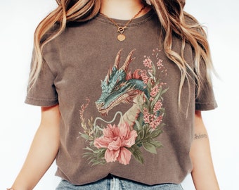 May include: A brown t-shirt with a graphic print of a blue and green dragon surrounded by pink and white flowers.