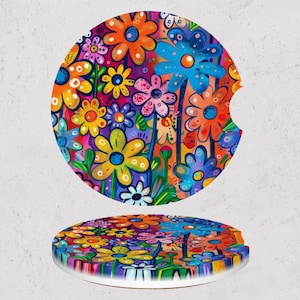 May include: Two colorful car coasters with a vibrant floral design. The coasters feature a variety of flowers in shades of orange, blue, yellow, pink, and purple. The design is a bright and cheerful addition to any vehicle's interior.