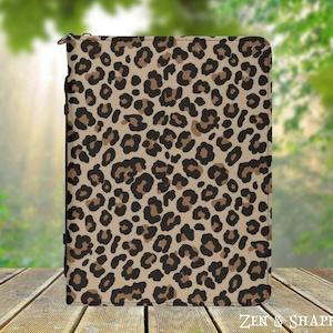 May include: A rectangular zippered case featuring a tan background with a repeating black and brown leopard print pattern. The case has a black zipper closure along the left side and the text ZEN & SHAPE printed in white in the bottom right corner.