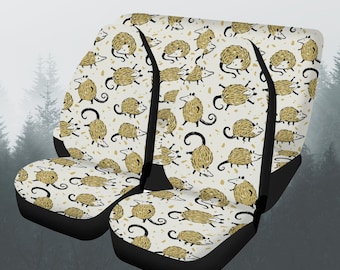 Puede incluir: Conjunto de tres fundas para asientos de coche beige con un patrón de zarigüeya negro y dorado. Las fundas tienen correas elásticas negras y una parte inferior negra.