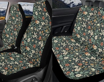 May include: A set of two black car seat covers with a floral pattern featuring a variety of flowers and leaves in shades of green, white, and pink on a dark background.