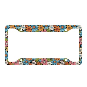 May include: A rectangular license plate frame featuring a repeating pattern of colorful flowers in shades of blue, orange, pink, and white against a black background. The frame has four circular mounting holes, one in each corner.