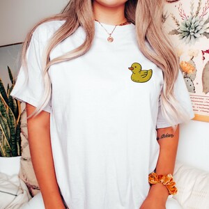 May include: White t-shirt with a yellow rubber ducky graphic on the front.
