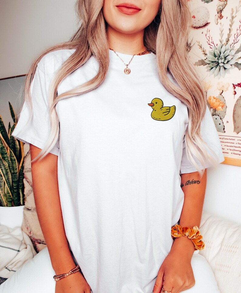 May include: White t-shirt with a yellow rubber ducky graphic on the front.