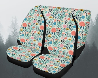 May include: Set of three car seat covers with a floral pattern featuring pink, blue, and yellow flowers on a white background. The covers have black edging.