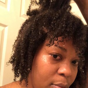 May include: A close-up of a person with wet, curly hair. The person is looking at the camera with a serious expression.