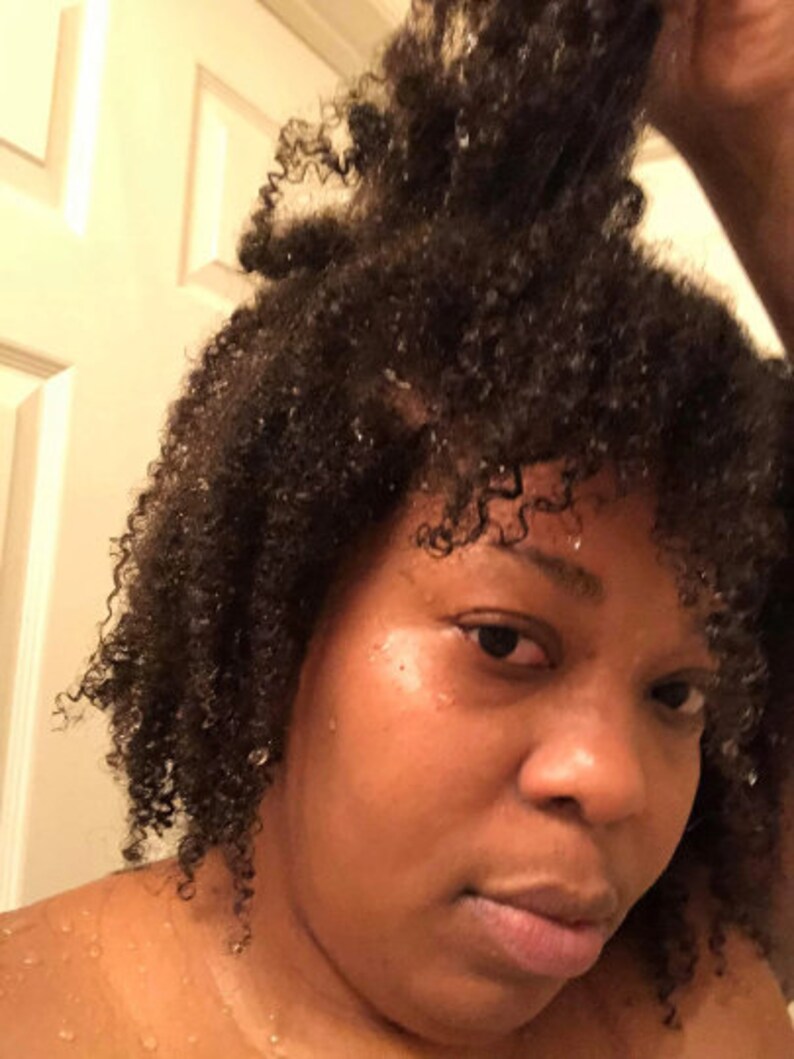 May include: A close-up of a person with wet, curly hair. The person is looking at the camera with a serious expression.