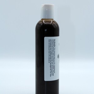 May include: A brown bottle of hair wash with a white label. The label reads "Key Benefits: This cleansing wash is a rich, cleansing and moisturising shampoo with no parabens or sulphates. This wash nourishes and re-energises the scalp with natural peppermint and rosemary oils, purifying brittle and damaged hair. Our wash does not strip your hair or its natural oil."