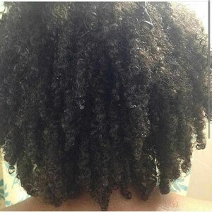 May include: Close-up of a person's dark curly hair. The hair is styled in a short, curly bob.