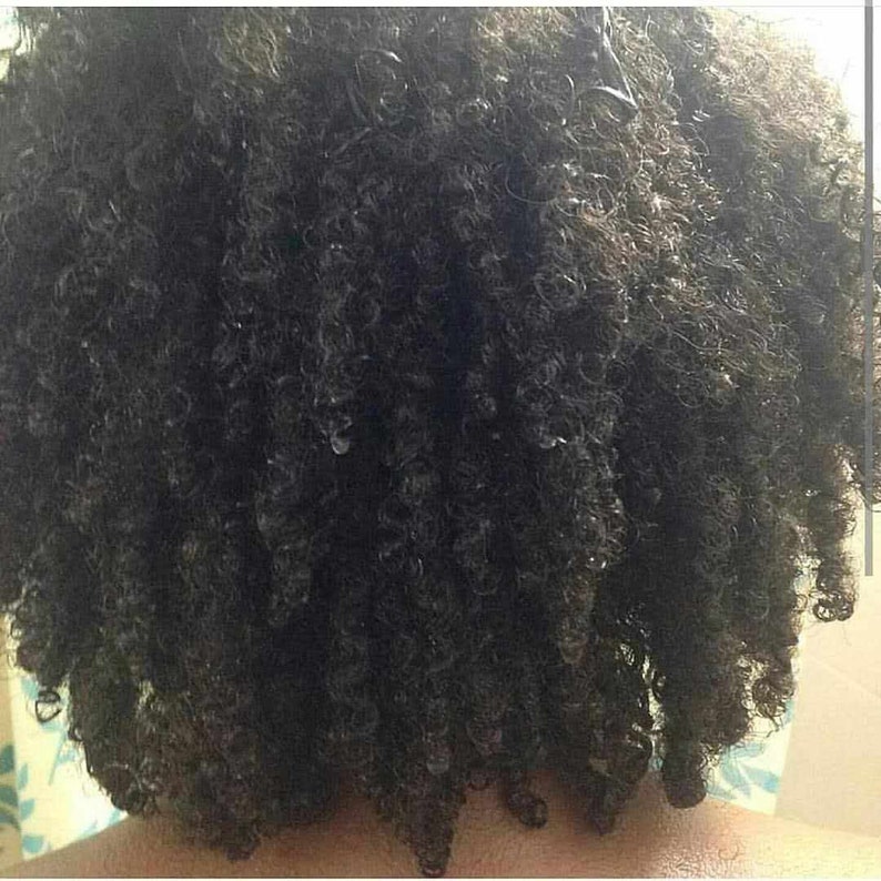 May include: Close-up of a person's dark curly hair. The hair is styled in a short, curly bob.