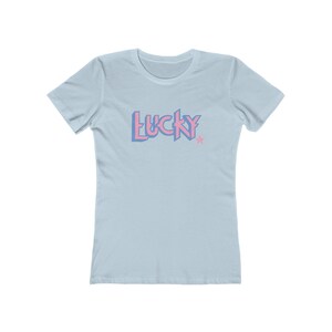 May include: A light blue t-shirt with a pink and blue "LUCKY" graphic with a star.