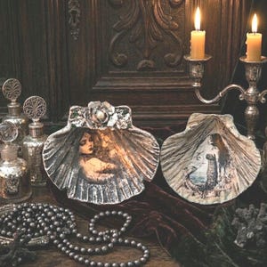 May include: A white ceramic mug with a black handle and the text "But First, Coffee" in a black, bold font. The mug is on a white surface.