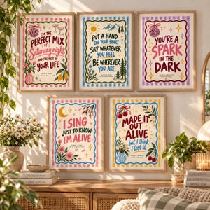Pode incluir: Cinco impressões de arte de parede retangulares com ilustrações coloridas e letras de músicas. Os cartazes exibem bordas decorativas, motivos florais e texto, incluindo "I'm the perfect mix of Saturday night" e "You're a spark in the dark."