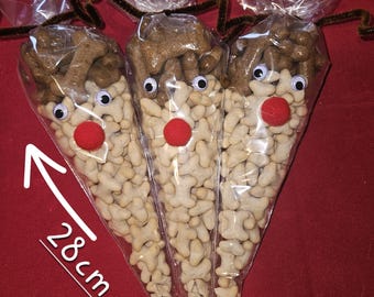 May include: Three clear cellophane bags filled with snacks, decorated to resemble reindeer. Each bag has googly eyes, a red pom-pom nose, and brown pipe cleaner antlers. The bags are approximately 11 inches long.