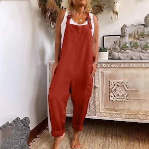 a woman standing in a room wearing a red jumpsuit