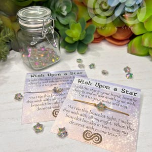 May include: Two "Wish Upon a Star" bracelets with a star-shaped charm and a jar filled with iridescent confetti. The cards include text about making a wish. The background features green and blue succulents.
