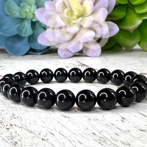 May include: Black onyx beaded bracelet with a polished finish. The bracelet is made of round beads and is approximately 7 inches in length.