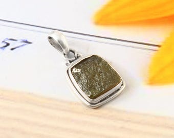 May include: A silver pendant with a green, rough-cut gemstone set in a silver frame.
