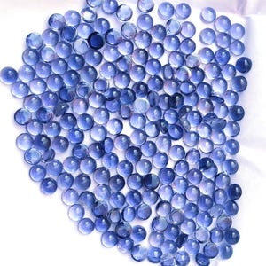Peut inclure: Un ensemble de petits galets de verre ronds bleus, disposés sur une surface blanche. Les galets sont translucides, avec des nuances de bleu. Ces galets décoratifs peuvent être utilisés pour l'artisanat ou la décoration intérieure.