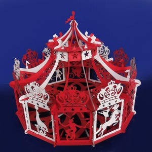Peut inclure: Un carrousel en papier rouge et blanc avec des détails complexes et un sommet en forme d'étoile. Le carrousel présente un cheval blanc et un cavalier, un vélo rouge et blanc et d'autres éléments décoratifs.