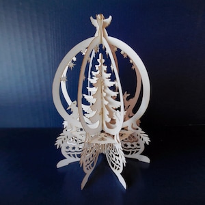 Könnte beinhalten: Ein lasergeschnittener Weihnachtsbaumschmuck aus Holz mit einem zentralen Weihnachtsbaum, Hirschen und Sternen. Der Schmuck hat einen Engel an der Spitze und ist aus hellem Holz gefertigt. Das Design ist aufwendig und detailliert, ideal für die Weihnachtsdekoration.