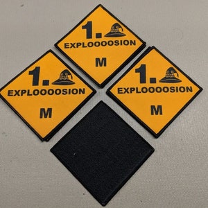 May include: Three yellow diamond-shaped patches with black borders and the text "1. EXPLOOOOOSION M" and a black cartoon image of a wizard's hat. A black diamond-shaped patch is in the center.