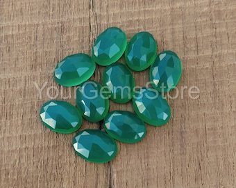 May include: A group of ten oval-shaped green gemstones, likely chalcedony, on a wooden surface.