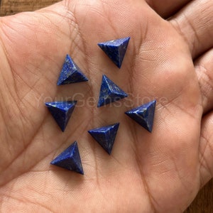 May include: Eight blue lapis lazuli pyramid shaped gemstones. The gemstones are small and have a smooth, polished surface.