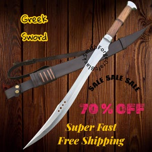 May include: A Greek sword with a curved, silver blade and a wooden handle. The sword is displayed with a brown leather sheath and strap against a wooden background. Text on the image reads "Greek Sword" and "SALE".