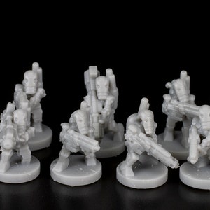 May include: A set of ten grey plastic miniature figures of robots with guns. The figures are standing on round bases.