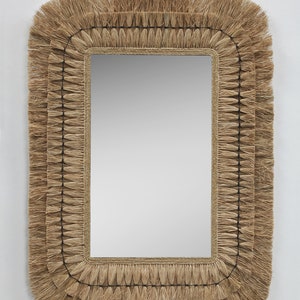 Könnte beinhalten: Rechteckiger Spiegel mit einem Rahmen aus Naturfasern. Der Rahmen hat ein mehrschichtiges Design mit einer Fransenstruktur in Beige- und Brauntönen. Die reflektierende Oberfläche des Spiegels ist glatt und klar, vor weißem Hintergrund.