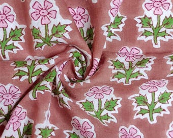 Può includere: Un primo piano di un tessuto con stampa floreale rosa e verde. Il tessuto ha uno sfondo marrone chiaro con un motivo ripetitivo di fiori rosa con foglie verdi.