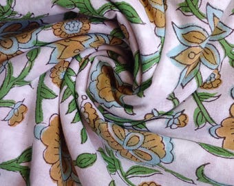 May include: A close-up of a pink fabric with a floral pattern. The flowers are yellow, blue, and green. The fabric is soft and has a smooth texture.