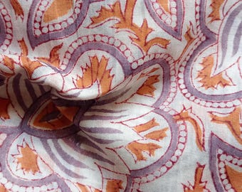May include: White fabric with a repeating pattern of orange and purple floral designs. The fabric is folded and textured.