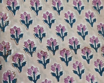 May include: Close-up of a fabric with a repeating floral pattern. The flowers are a soft purple color with dark teal stems and leaves. The background is a light beige color.