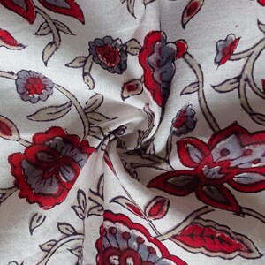 May include: White fabric with a red and gray floral pattern. The fabric is folded and shows the pattern on both sides.
