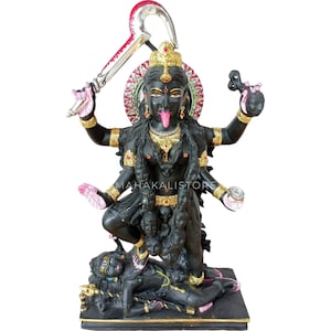 May include: Black stone statue of the Hindu goddess Kali, with four arms, standing on a demon. She is holding a sword, a skull, and a bowl. She has a fierce expression and a long, red tongue.