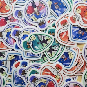 May include: A collection of colorful heart-shaped and round stickers featuring illustrations of bottles with different colored liquids and characters inside. The bottles have labels with words like "Love", "Courage", and "Hope".