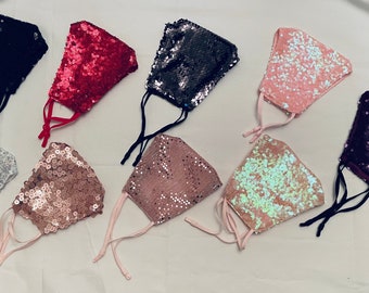 May include: Assortment of eight sequined face masks in various colors, including black, red, silver, pink, brown, purple, and iridescent.