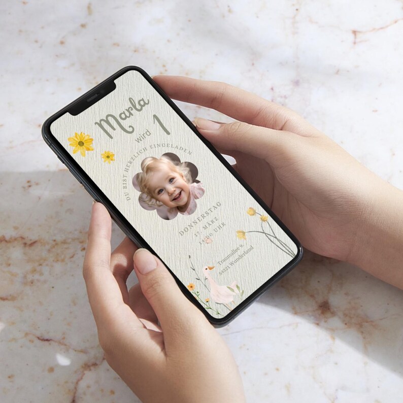 Puede incluir: Un tel&eacute;fono inteligente que muestra una invitaci&oacute;n de cumplea&ntilde;os para una ni&ntilde;a llamada Marla que cumple un a&ntilde;o. La invitaci&oacute;n presenta una foto de la ni&ntilde;a, un dise&ntilde;o floral y el texto "Marla wird 1" y "Du bist herzlich eingeladen".