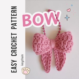Op de afbeelding: Een roze gehaakte strik-sleutelhanger met een bijpassende roze kogelketting. De afbeelding bevat de tekst "EASY CROCHET PATTERN" verticaal aan de linkerkant, het woord "BOW" in grote roze letters, het woord "keychain" eronder en een klein pootafdruk-icoon.