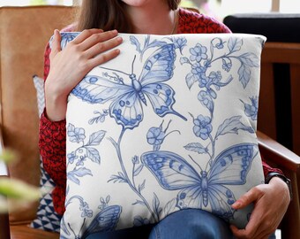 Puede incluir: Una almohada blanca con un patrón floral azul y blanco con mariposas. La almohada está hecha de tela suave y cómoda y es perfecta para agregar un toque de elegancia a cualquier habitación.