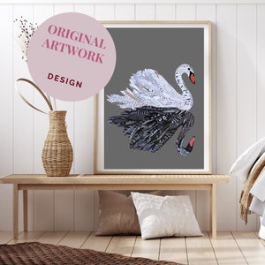 May include: A black and white paper collage of two swans, one black and one white, with their necks intertwined. The swans are on a grey background and are framed in a white frame. The artwork is hanging on a white wall above a wooden bench.