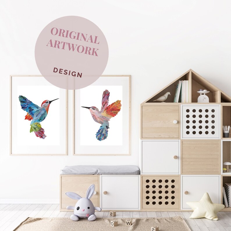 May include: Two framed prints of colorful hummingbird illustrations, one with a blue and green hummingbird and the other with a red and orange hummingbird. The prints are hanging on a white wall above a wooden bench with a white cushion.